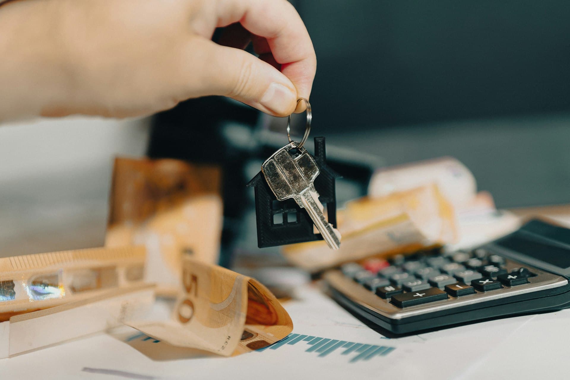 Llave de propiedad junto a calculadora – tarifas de administración inmobiliaria